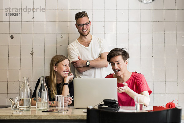 Junge Geschäftsleute diskutieren über Laptop im Kreativbüro