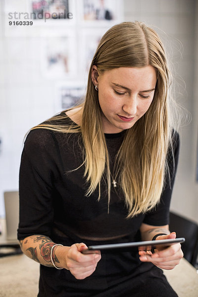 Junge Geschäftsfrau mit digitalem Tablett im Kreativbüro