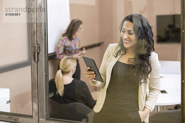 Glückliche Geschäftsfrau mit digitalem Tablett im Kreativbüro