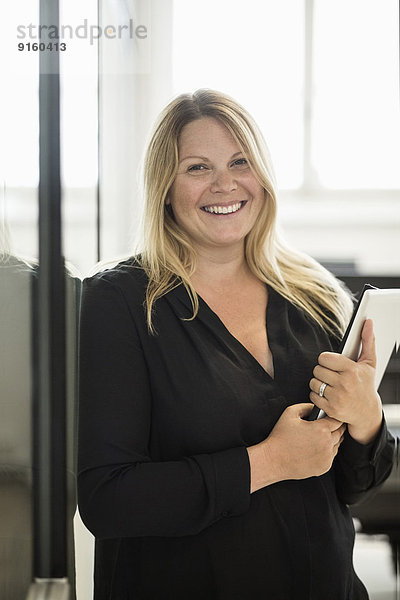 Porträt einer glücklichen Geschäftsfrau mit digitalem Tablett im Kreativbüro