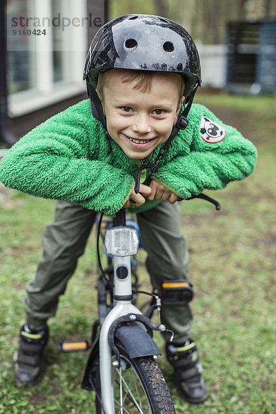 Porträt eines glücklichen Jungen mit Helm beim Radfahren