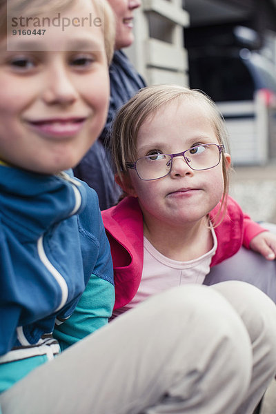 Mädchen mit Down-Syndrom beim Anblick des Bruders im Freien