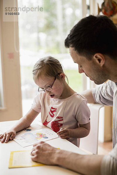 Vater hilft behinderten Mädchen beim Lernen zu Hause
