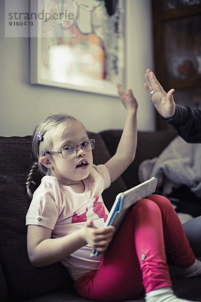 Porträt des Mädchens  das der Mutter auf dem Sofa High-Five gibt