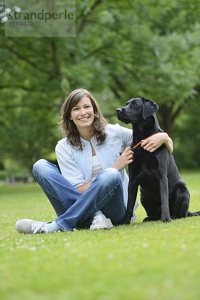 Frau mit einem schwarzen Labrador auf einer Wiese  Bayern  Deutschland  Europa