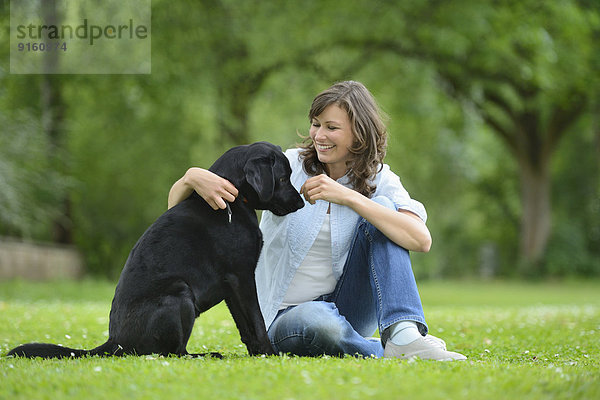 Frau mit einem schwarzen Labrador auf einer Wiese  Bayern  Deutschland  Europa