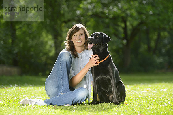 Frau mit einem schwarzen Labrador auf einer Wiese  Bayern  Deutschland  Europa