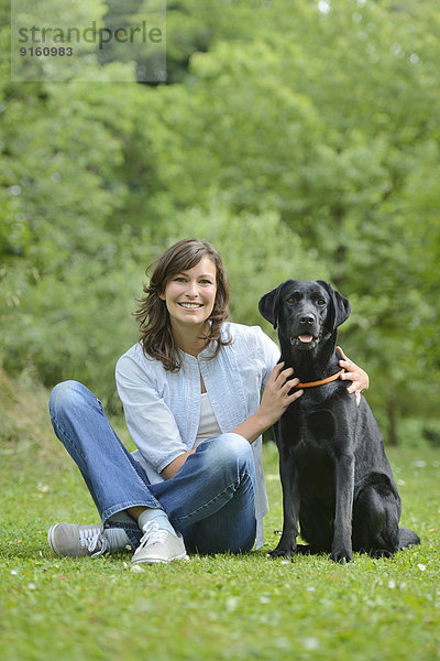 Frau mit einem schwarzen Labrador auf einer Wiese  Bayern  Deutschland  Europa