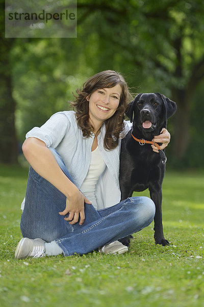 Frau mit einem schwarzen Labrador auf einer Wiese  Bayern  Deutschland  Europa