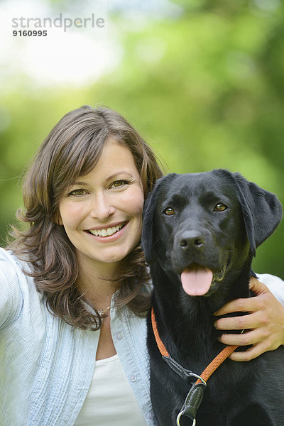 Frau mit einem schwarzen Labrador auf einer Wiese  Bayern  Deutschland  Europa