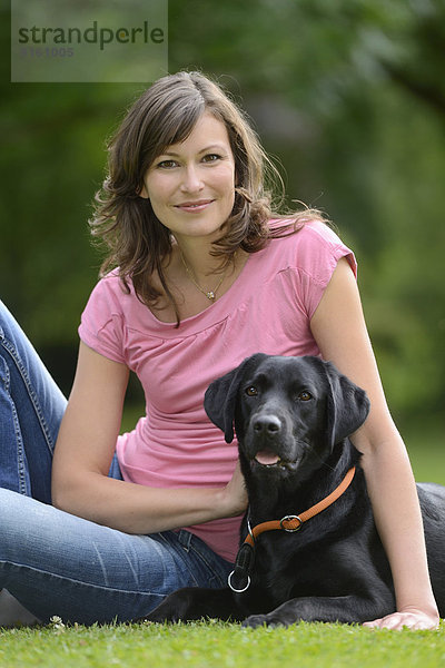 Frau mit einem schwarzen Labrador auf einer Wiese  Bayern  Deutschland  Europa