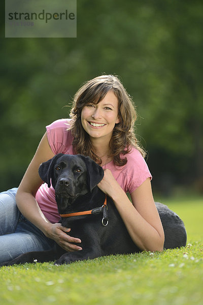 Frau mit einem schwarzen Labrador auf einer Wiese  Bayern  Deutschland  Europa