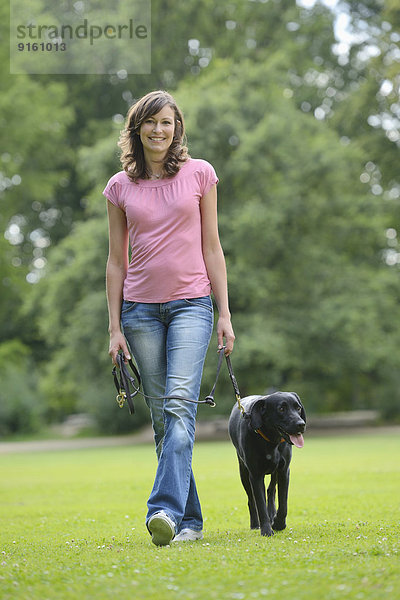 Frau mit einem schwarzen Labrador auf einer Wiese  Bayern  Deutschland  Europa