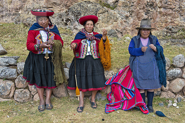 Drei ältere Frauen mit Hüten  Quechua-Indianer in traditioneller Kleidung spinnen mit Holzspindeln Wolle  Cinchero  Urubambatal  Peru