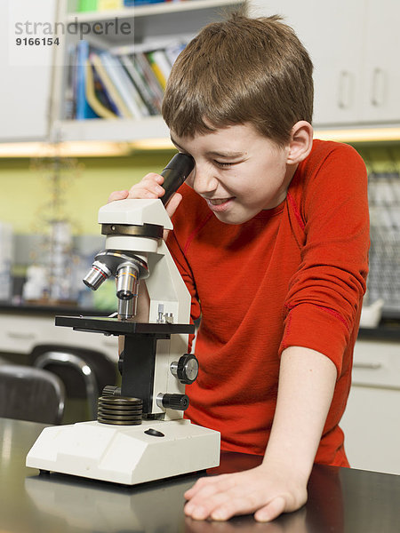 Caucasian boy using microscope in chemistry lab