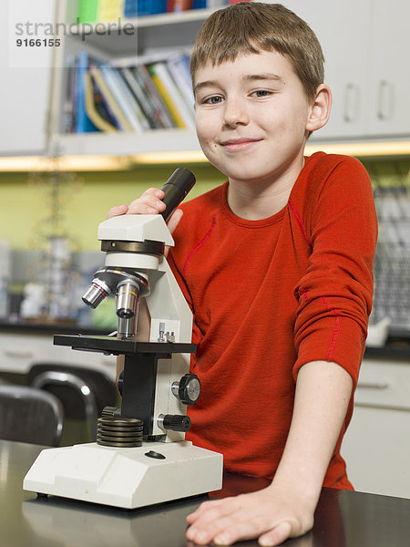 Caucasian boy using microscope in chemistry lab