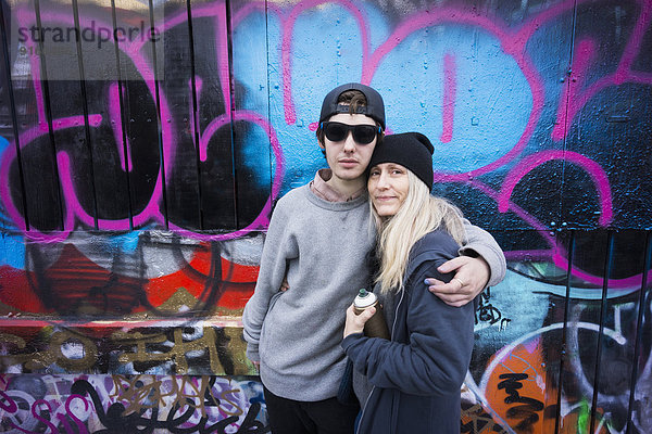 Caucasian mother and son hugging by graffiti wall