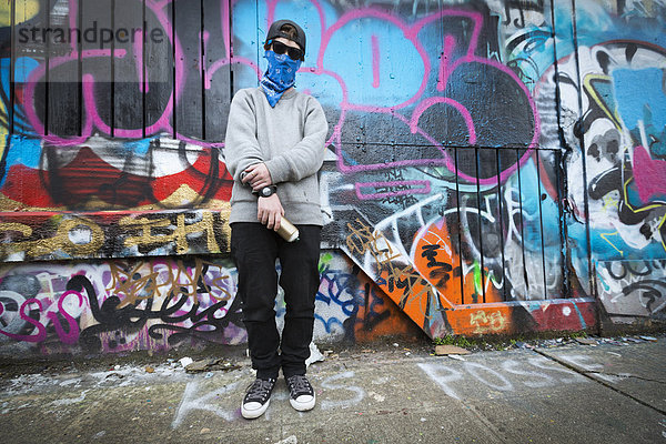 Caucasian teenage boy standing by graffiti wall