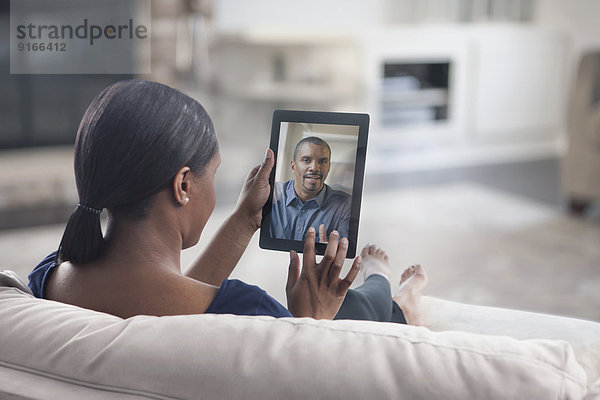 Woman video conferencing with father on digital tablet