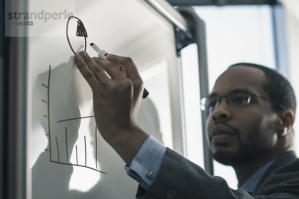 Businessman writing on whiteboard in office