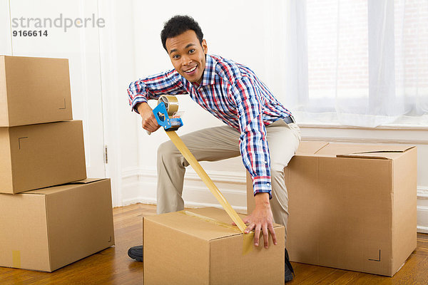 Mixed race man packing cardboard boxes