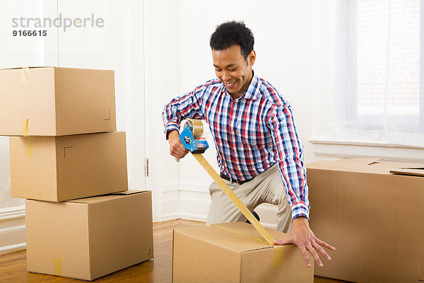 Mixed race man packing cardboard boxes