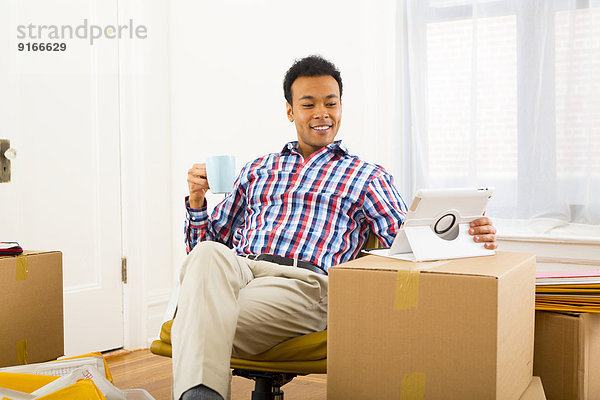 Mixed race man using digital tablet and having cup of coffee