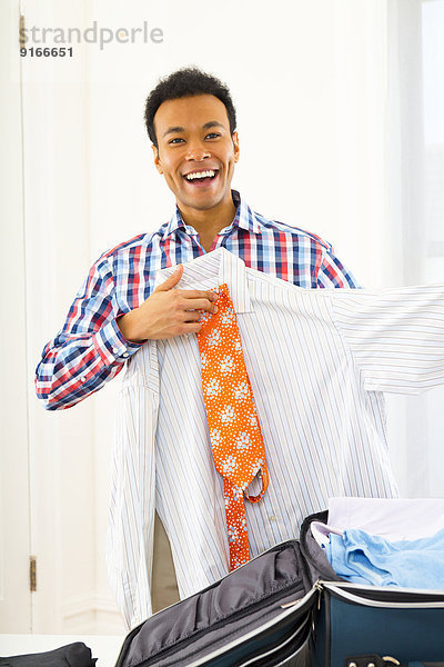 Mixed race businessman packing suitcase