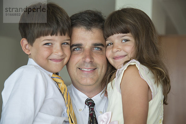 Caucasian father and children smiling in formal wear