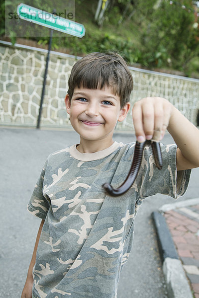 Caucasian boy holding millipede outdoors