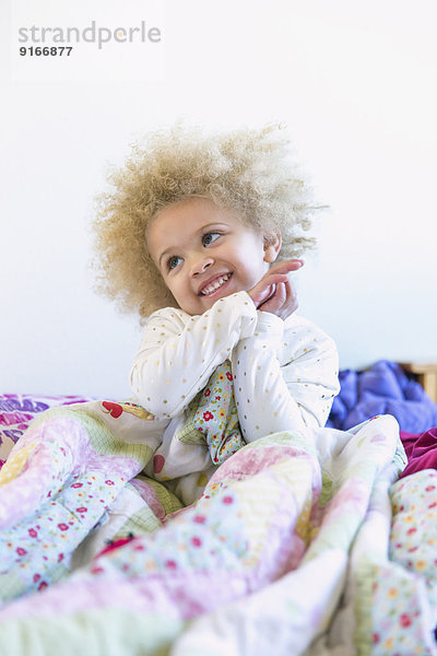 Mixed race girl smiling in bed