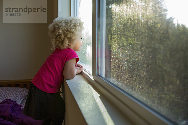 Mixed race girl looking out window