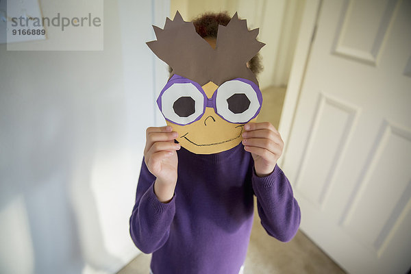 Mixed race girl holding mask over face