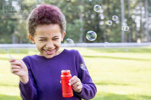 Mixed race girl blowing bubbles outdoors