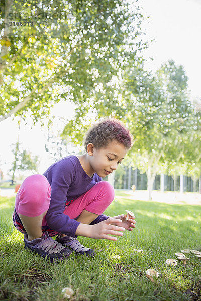 Mixed race girl examining mushrooms outdoors