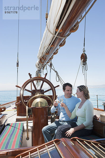 Caucasian couple toasting each other on sailboat