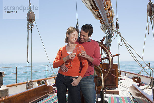 Caucasian couple toasting each other on sailboat