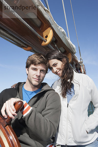 Caucasian couple steering sailboat