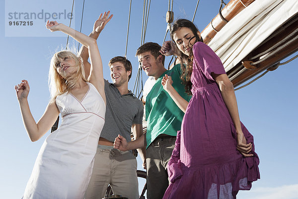 Caucasian friends dancing on sailboat