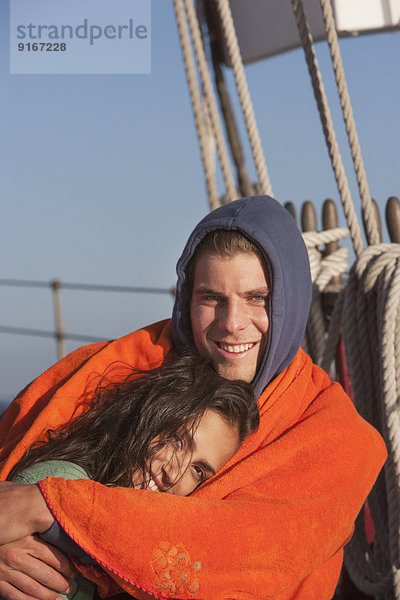 Caucasian couple wrapped in blanket on sailboat