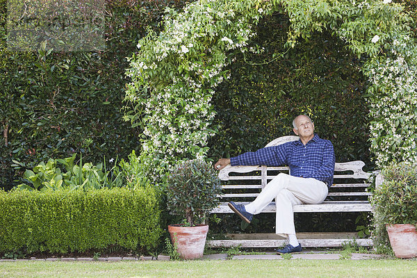 Senior Caucasian man sitting on garden bench