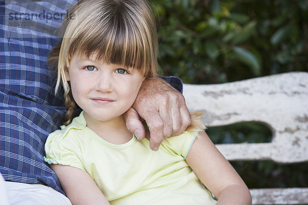 Caucasian girl sitting with grandfather on bench