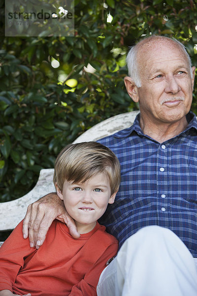 Caucasian boy sitting with grandfather on bench