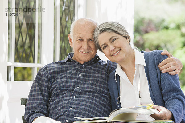 Senior Caucasian couple reading outdoors