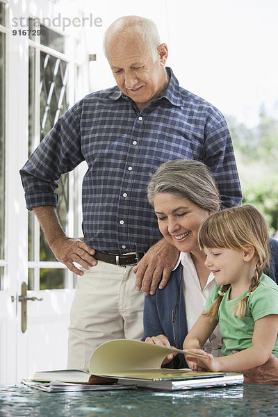 Grandparents and granddaughter reading outdoors