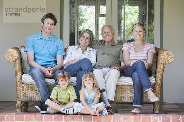 Caucasian multi-generation family smiling on porch