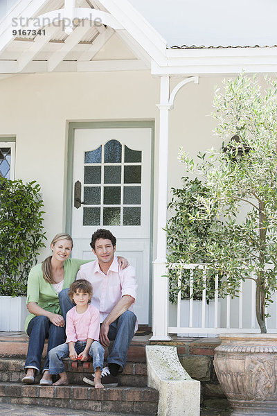 Caucasian family smiling on front steps