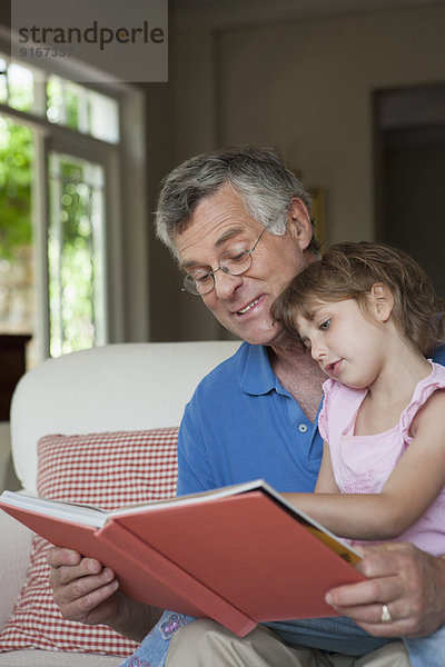 Caucasian man reading to granddaughter