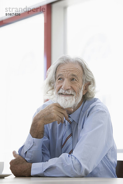 Senior Caucasian businessman smiling at desk