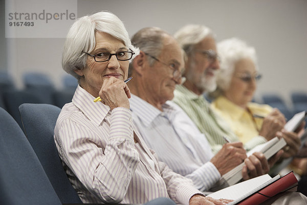 Senior Caucasian students taking notes in classroom